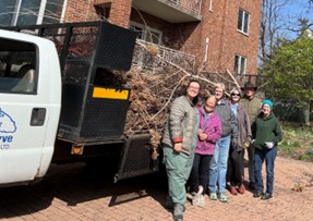 Garden volunteers in front of a truck bed full of branches and weeds.